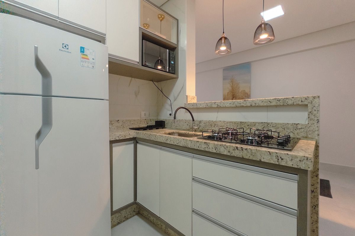 A compact kitchen with a built-in microwave, a gas stove, and white cabinetry.