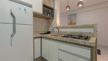 A compact kitchen with a built-in microwave, a gas stove, and white cabinetry.