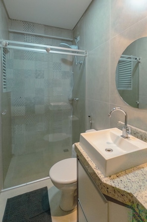 Un baño con cabina de ducha de vidrio, inodoro y lavabo con encimera de mármol.
