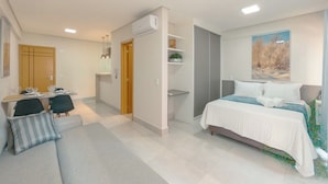 Quarto moderno com cama, escrivaninha e cadeira. Há uma janela com um quadro acima da cama.