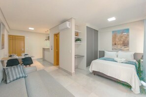 Un dormitorio moderno con cama, escritorio y silla. Hay una ventana con un cuadro sobre la cama.