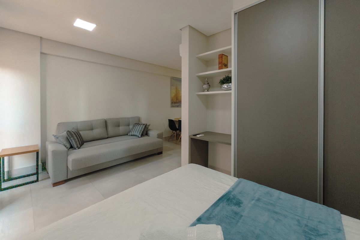 Quarto moderno com cama, sofá, escrivaninha e estante.