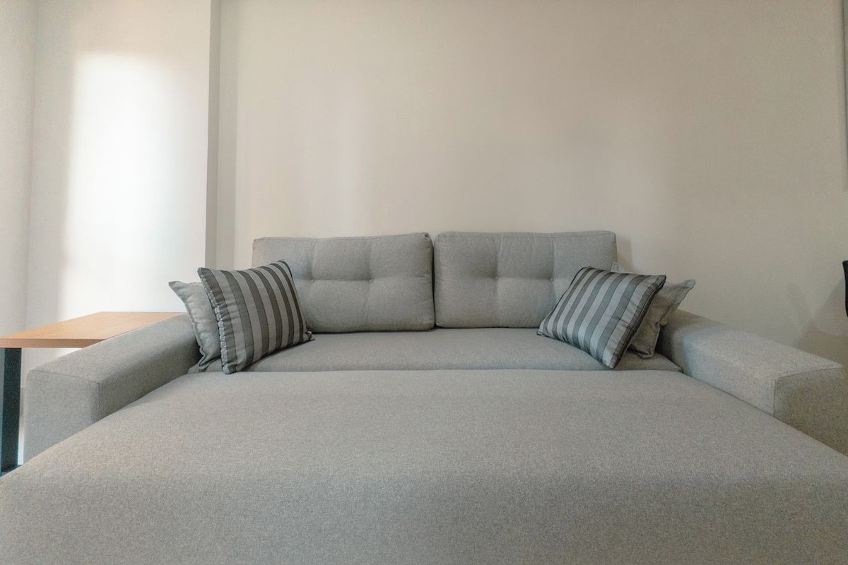 A modern, minimalist living room with a grey sofa and striped pillows.