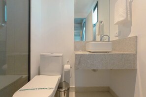 Uma casa de banho moderna com sanita, lavatório e espelho.