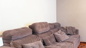 A sectional sofa in a room with a herringbone wooden floor and plain white walls.