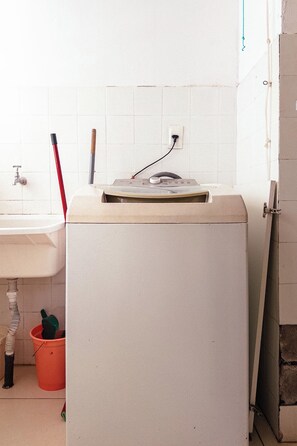 A kitchen with a white refrigerator, a sink, and a bucket.