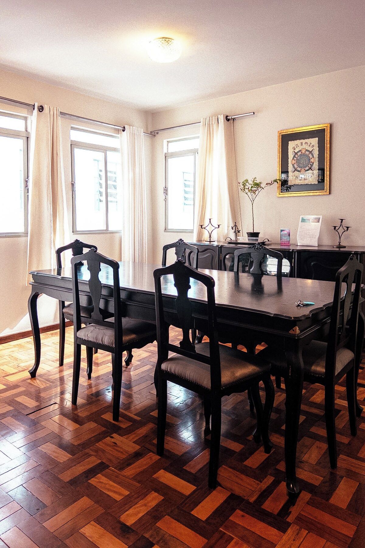 A dining area with a wooden herringbone floor, a dark wooden table, and matching chairs.