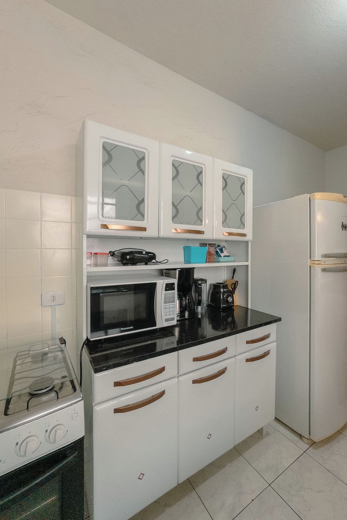 A compact kitchen with white cabinets, a microwave, a coffee maker, and a refrigerator.