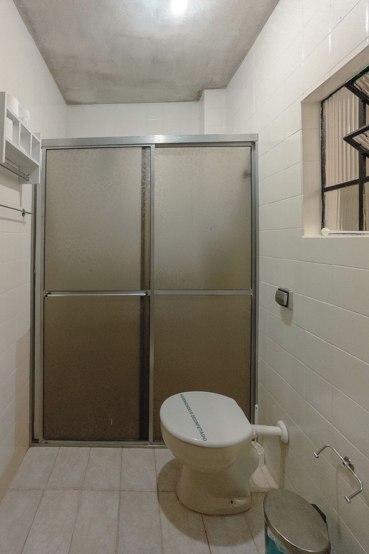 A bathroom with a toilet, a shower enclosure, and a window.