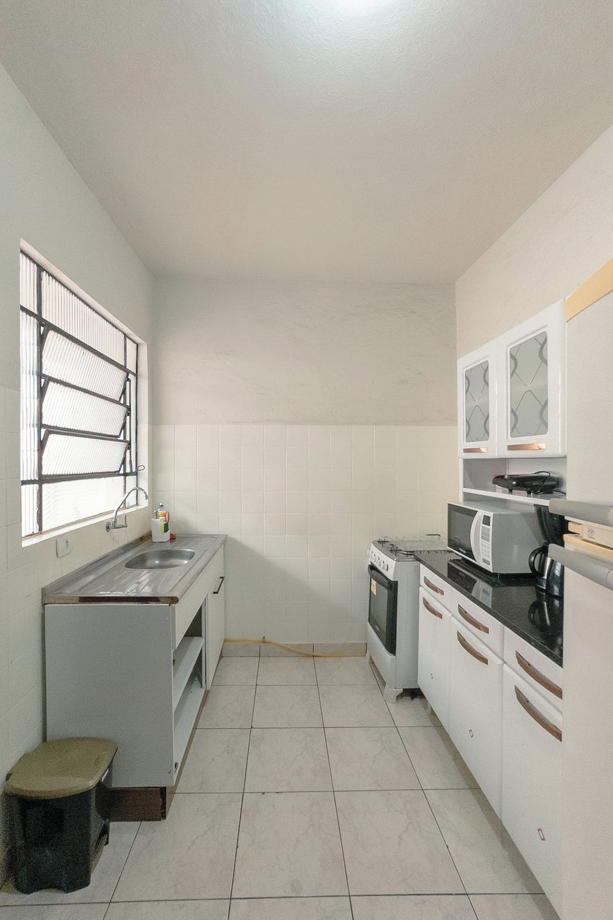 A compact kitchen with a sink, stove, microwave, and cabinets.