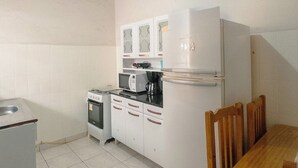 Cuina compacta amb fogó, microones, nevera i taula de menjador amb cadires.