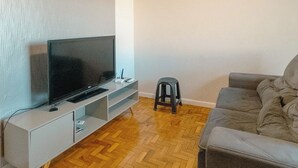Un saló amb televisió de pantalla plana, ventilador de sostre, sofà i terra de fusta amb relleu de guixineres.