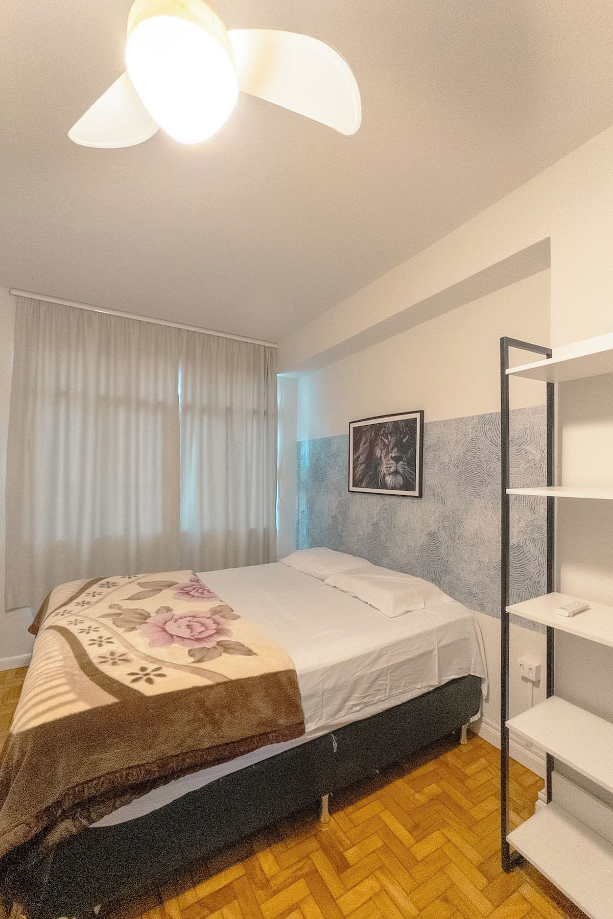 A bedroom with a bed, a bedside table, a wardrobe, and a ceiling fan.