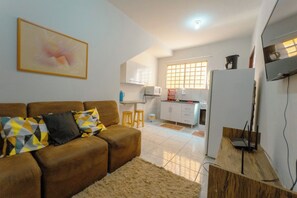 A living room with a brown sofa, a coffee machine, and a TV on a wooden stand.