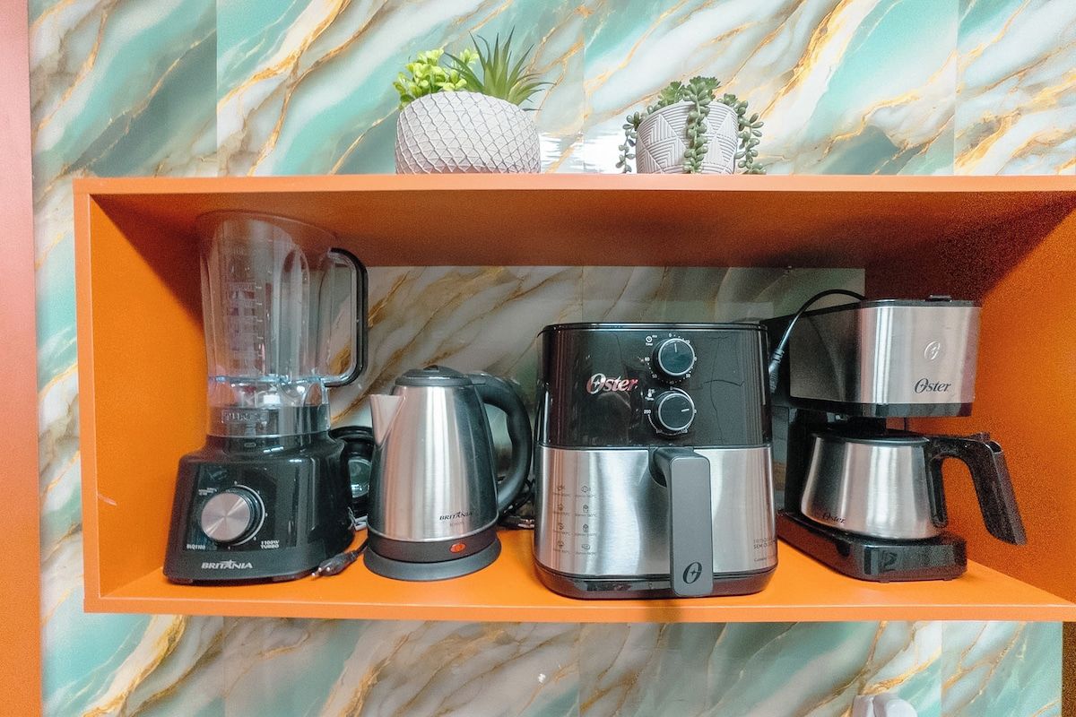 A shelf with a blender, a kettle, and two coffee makers.