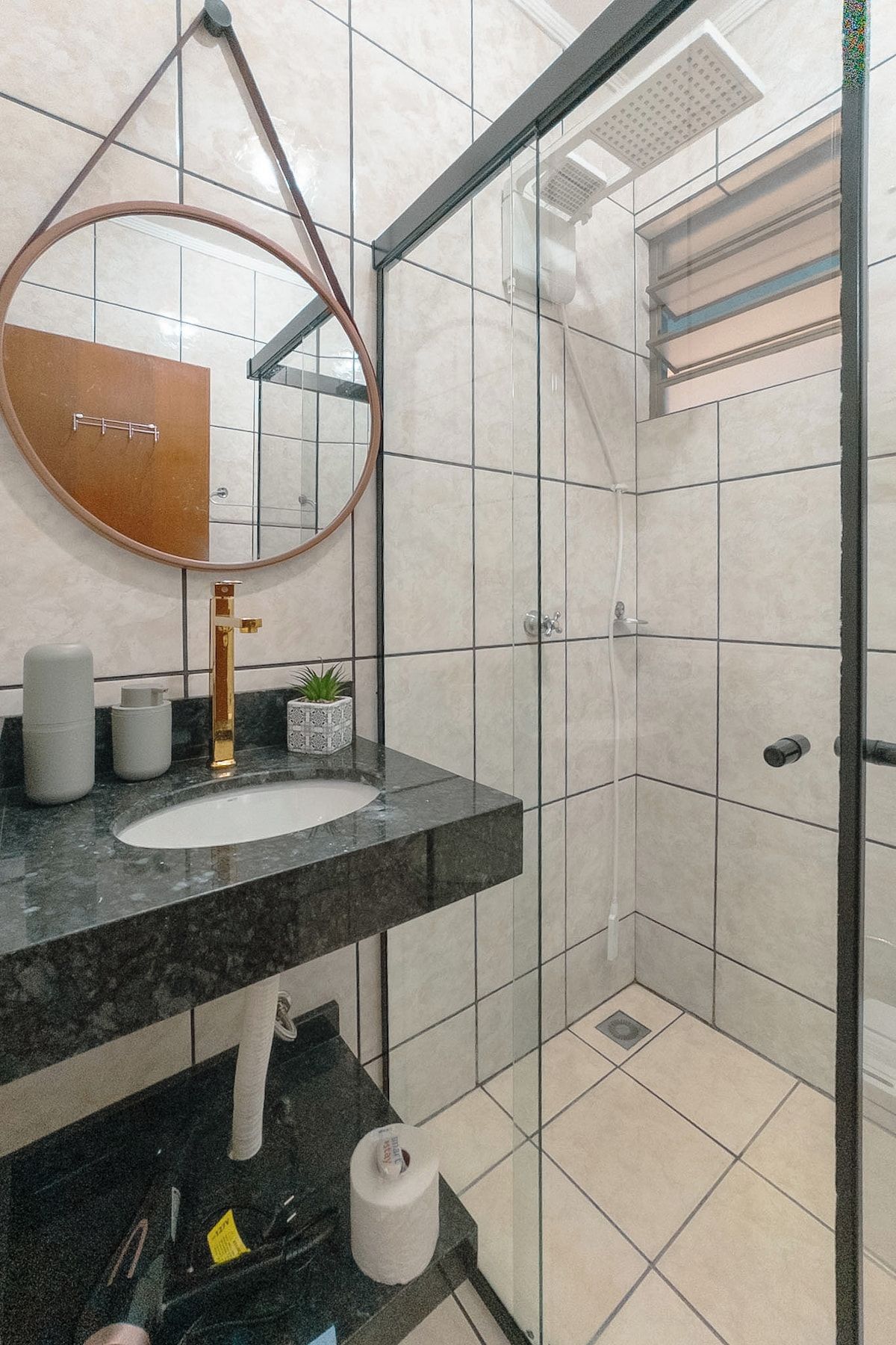 Un baño moderno con un espejo redondo, un lavabo, un inodoro y una zona de ducha.