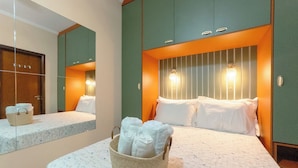 Una habitación de hotel con cama, mesita de noche, espejo y lámpara de pared.