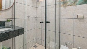 Un baño con cabina de ducha de vidrio, lavamanos de mármol y espejo.