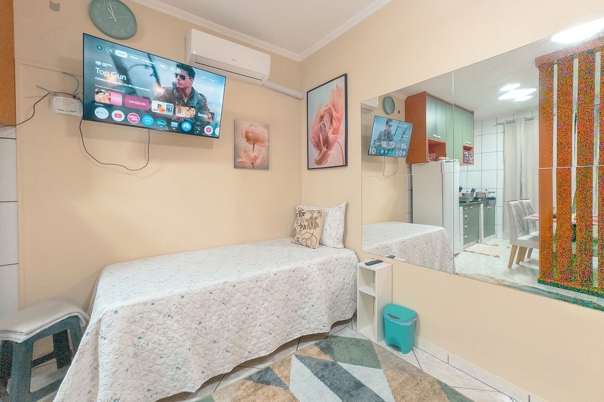 Un dormitorio con dos camas, un televisor montado en la pared, un espejo y una ventana con cortina.