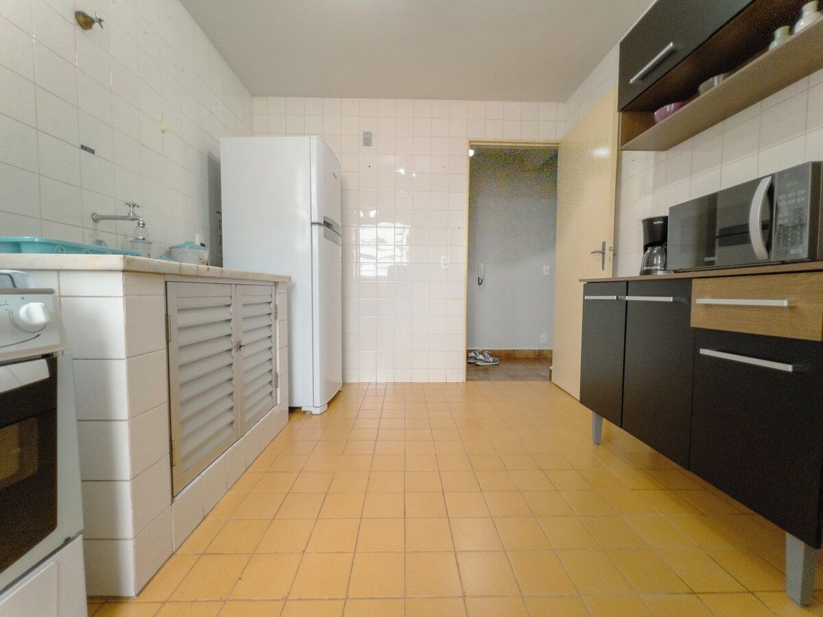 A kitchen with white cabinets, a refrigerator, a microwave, and a coffee maker.