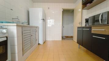 A kitchen with white cabinets, a refrigerator, a microwave, and a coffee maker.