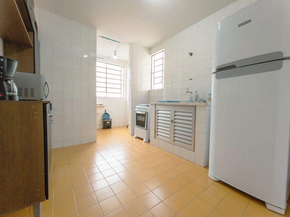 Una cocina con armarios blancos, un refrigerador, una cafetera y un horno pequeño.