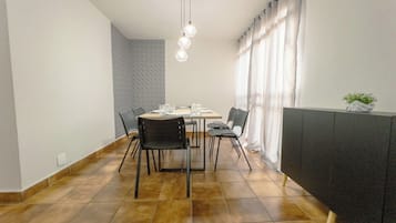 Een eethoek met een tafel, stoelen, een hanglamp en een radiator.