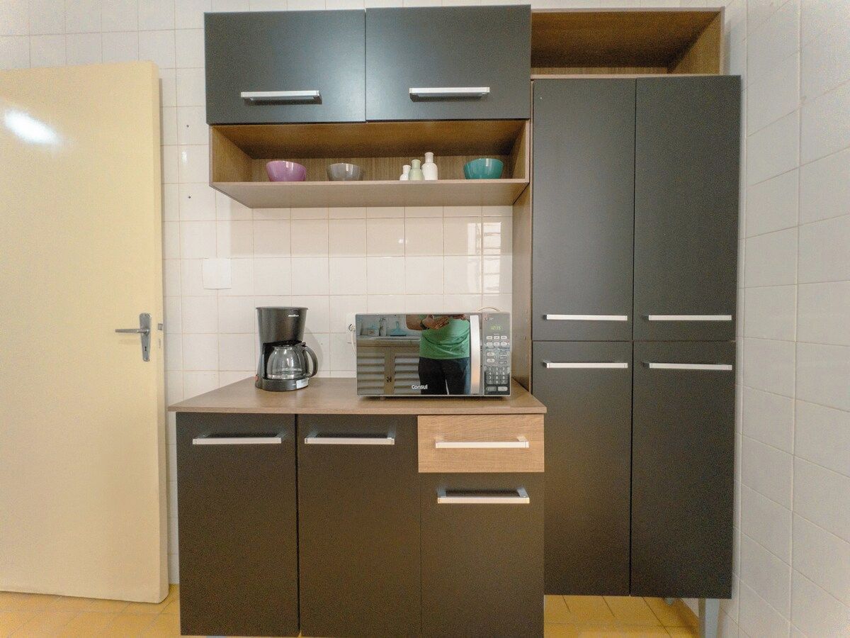 A compact kitchen with a microwave, coffee maker, and storage cabinets.