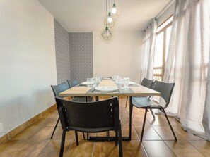 Ein Essbereich mit einem Tisch für vier Personen, Stühlen und hängenden Pendelleuchten.