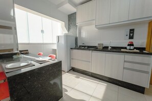 A modern kitchen with white cabinets, a black countertop, and a window providing natural light.