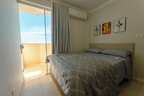 Een slaapkamer met een bed, een raam met gordijnen en drie kunstwerken aan de muur.