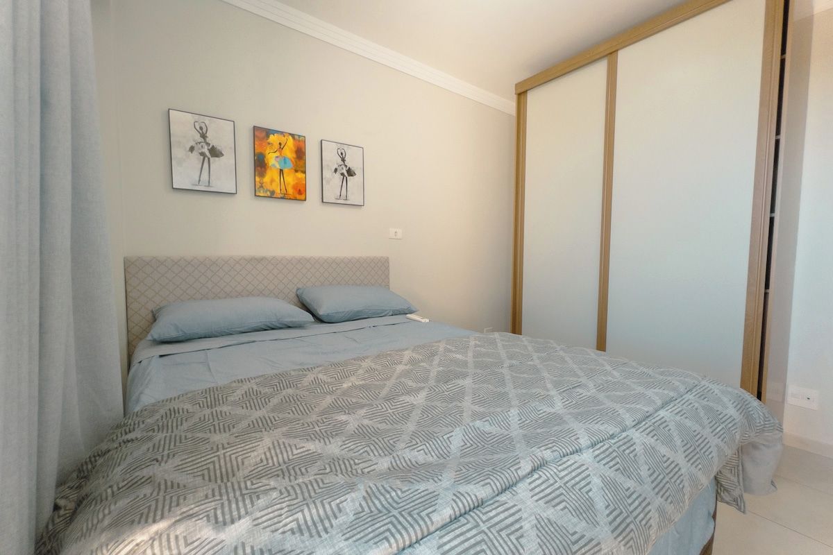 A bedroom with a bed, a headboard, and three wall-mounted artworks.