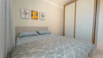 A bedroom with a bed, a headboard, and three wall-mounted artworks.