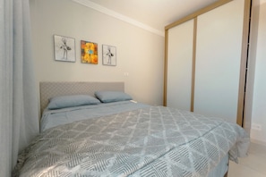 A bedroom with a bed, a headboard, and three wall-mounted artworks.