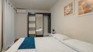 A hotel room with a bed, a blue towel, a shower area, and artwork on the wall. - Spacious Apartment beside Parque do Inga - MC31 (Maringá)