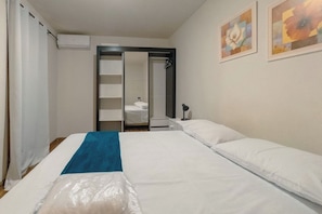 Habitación de hotel con cama, toalla azul, zona de ducha y obras de arte en la pared.
