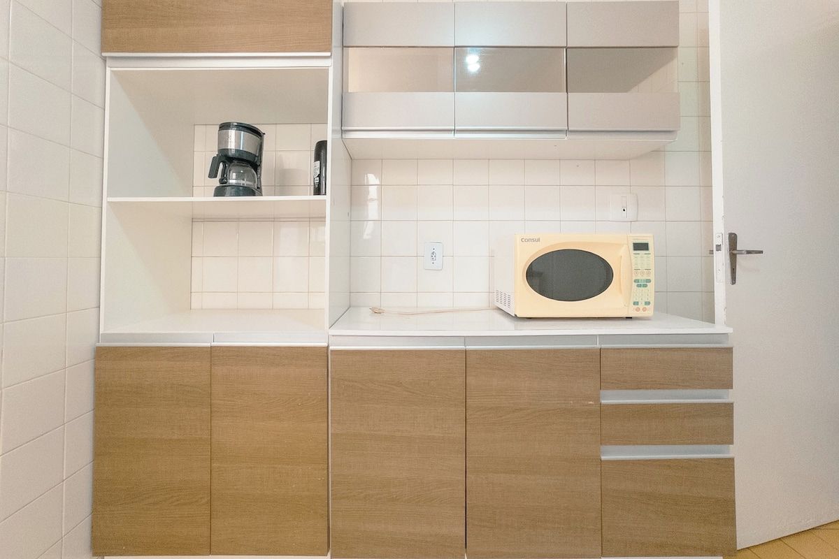 A compact kitchenette with a coffee maker, microwave, and wooden cabinets.