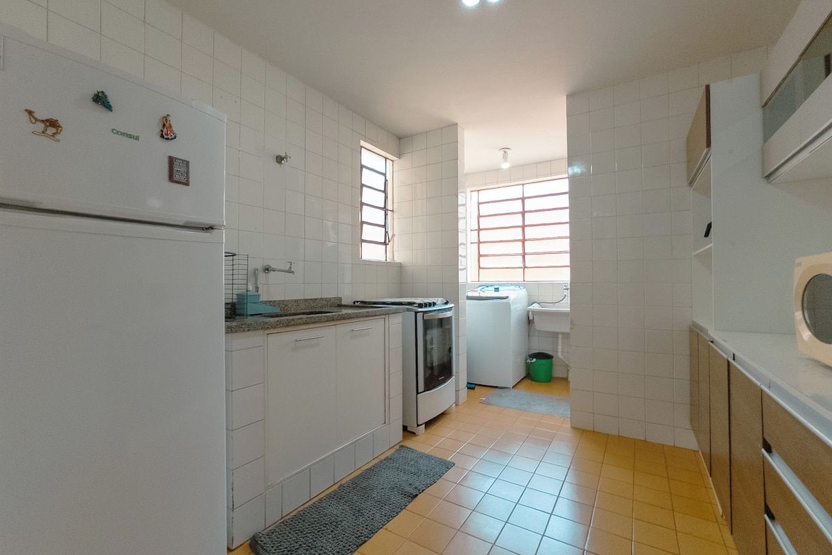 A kitchen with white cabinets, a refrigerator, a stove, and a window.