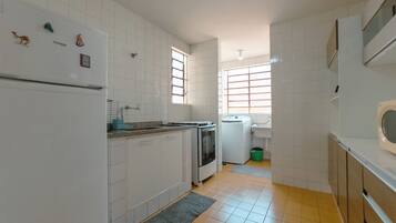 A kitchen with white cabinets, a refrigerator, a stove, and a window.