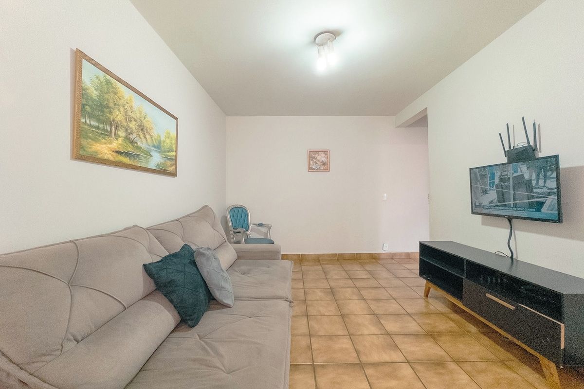 A living room with a sofa, a television, and a painting on the wall.