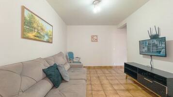 A living room with a sofa, a television, and a painting on the wall.