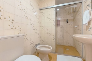 Un baño con inodoro, bidé y zona de ducha.