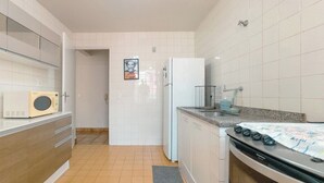 A compact kitchen with a microwave, refrigerator, and stove. - Spacious Apartment beside Parque do Inga - MC31 (Maringá)