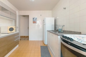 Cocina compacta con microondas, refrigerador y estufa.