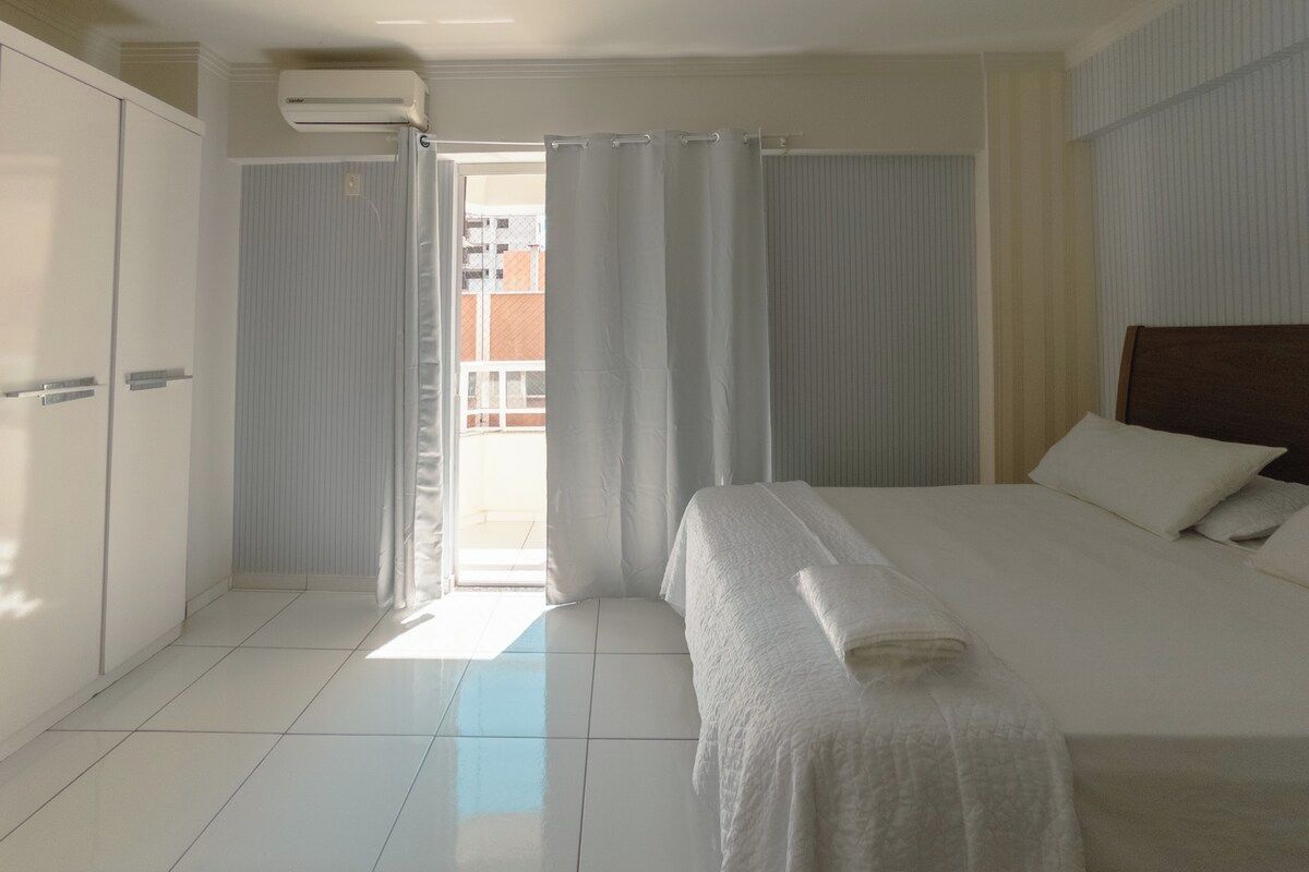 Ein Hotelzimmer mit Bett, Kleiderschrank, Bad und Blick nach draußen.