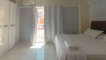 Ein Hotelzimmer mit Bett, Kleiderschrank, Bad und Blick nach draußen.