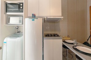 A compact kitchen with a microwave, a built-in oven, a refrigerator, and a gas stove. - Great Value Apartment in Zona 7 - GPAL207 (Maringá)