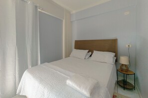 A hotel room with a large bed, a bedside table with a lamp, and a window with curtains. - Great Value Apartment in Zona 7 - GPAL207 (Maringá)
