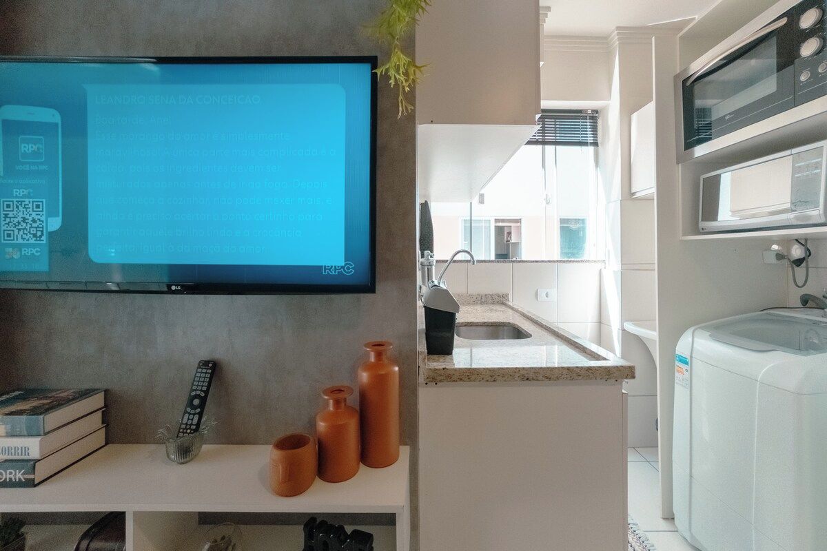 Een moderne keuken met een flatscreen televisie aan de muur, een spoelbak en een waterdispenser.