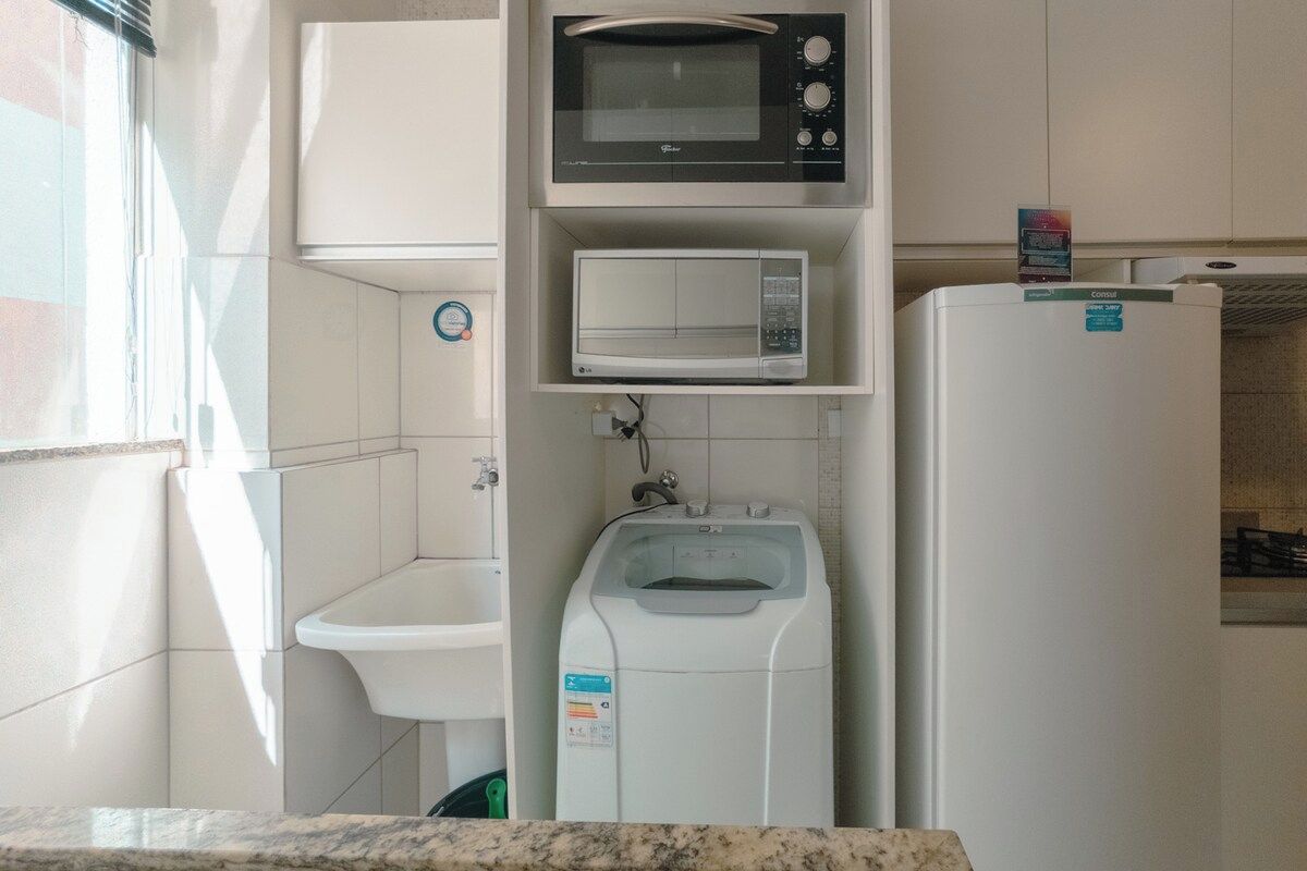 Eine kleine Küche mit einer Mikrowelle, einem Wasserspender und einem Kühlschrank.